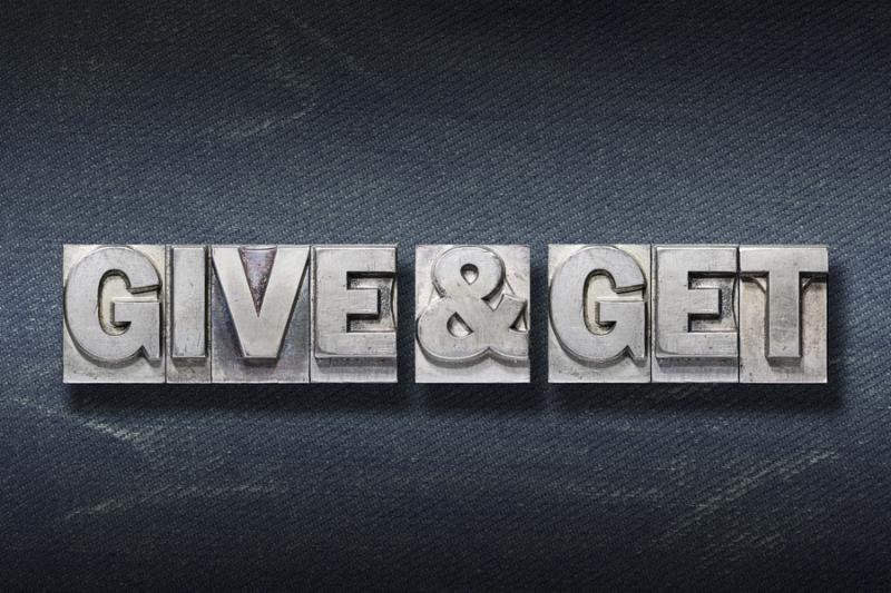 give and get phrase made from metallic letterpress on dark jeans background