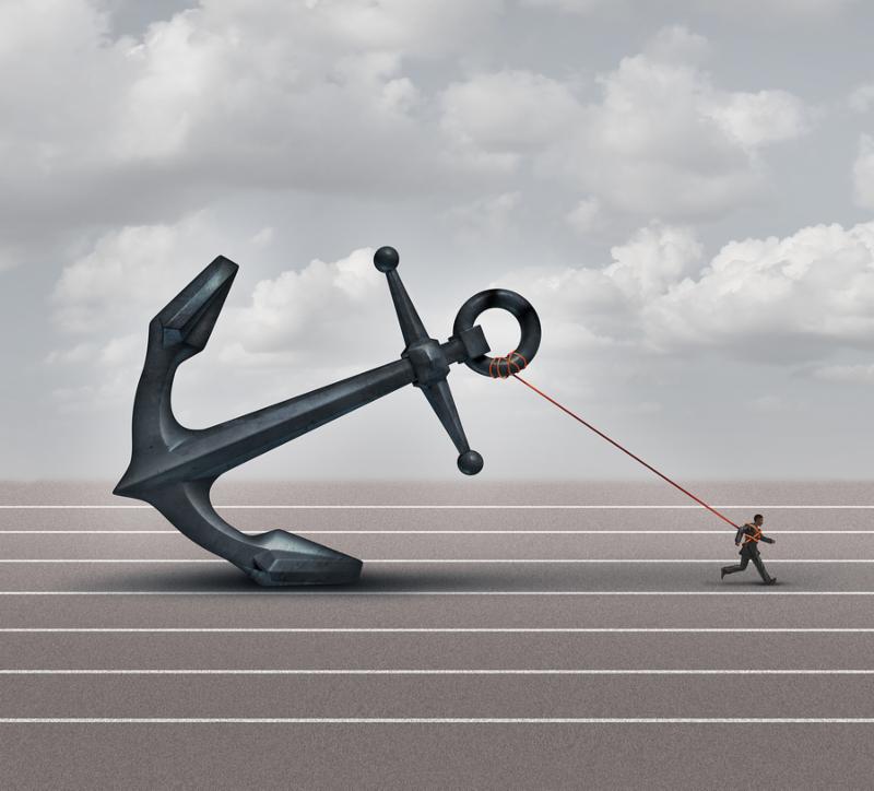 Career burden and business stress concept as a businessman or worker pulling a giant heavy metal anchor as a metaphor for hardship and struggle.