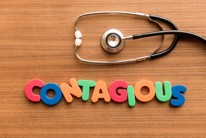 contagious colorful word on the wooden background with stethoscope